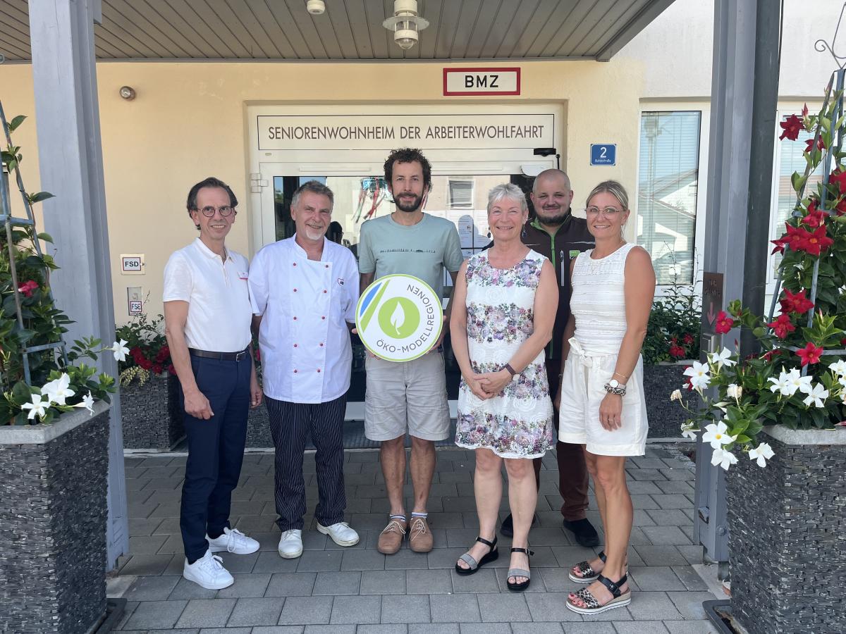 Gruppe von Menschen steht im Halbkreis vor Seniorenheim