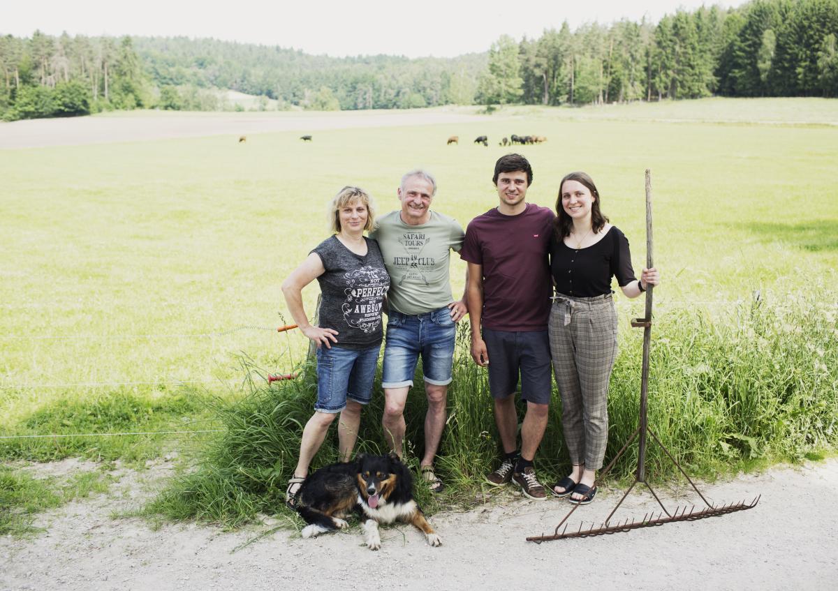 Vier Personen stehen vor einer Grünlandfläche.