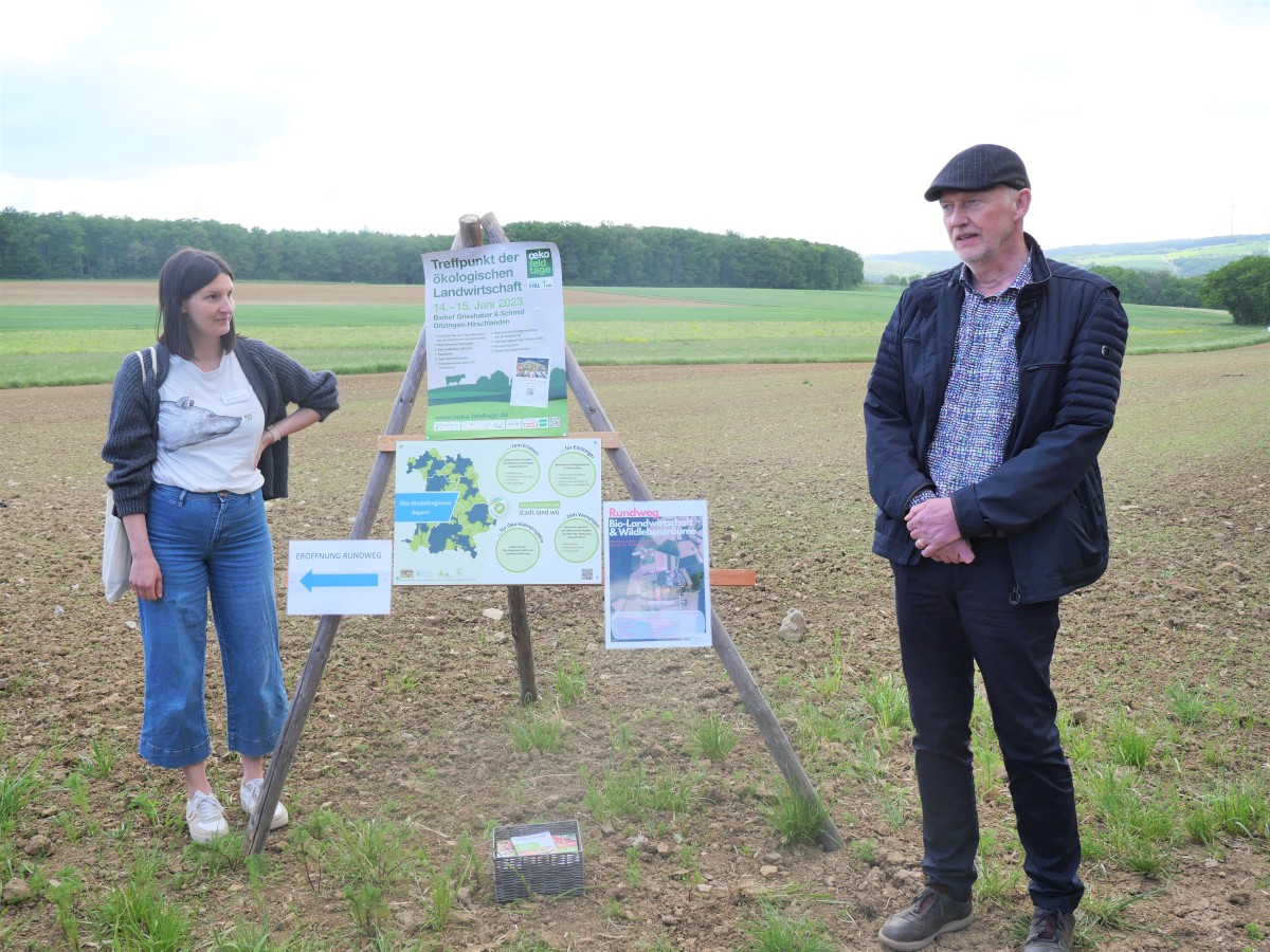 Personen präsentieren ein Schild am Feldrand