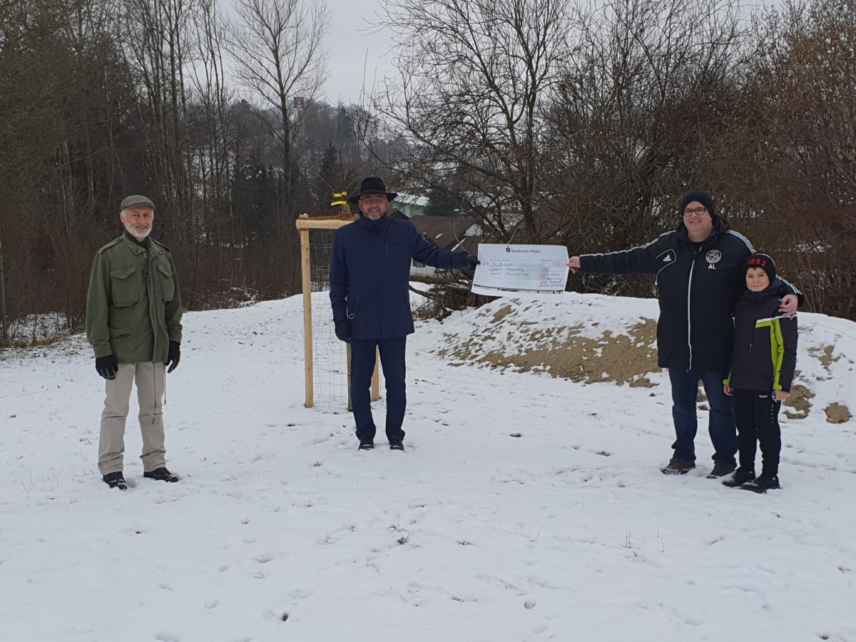 Bürgermeister Leveringhaus (Mitte) und Andreas Lutzenberger mit Sohn (rechts) bei der Spendenübergabe. Auch der Streuobstbeauftragte Albrecht Dörr (links) freut sich über den Zuwachs an Streuobstbäumen. Im Hintergrund ein Nisthügel für Wildbienen.