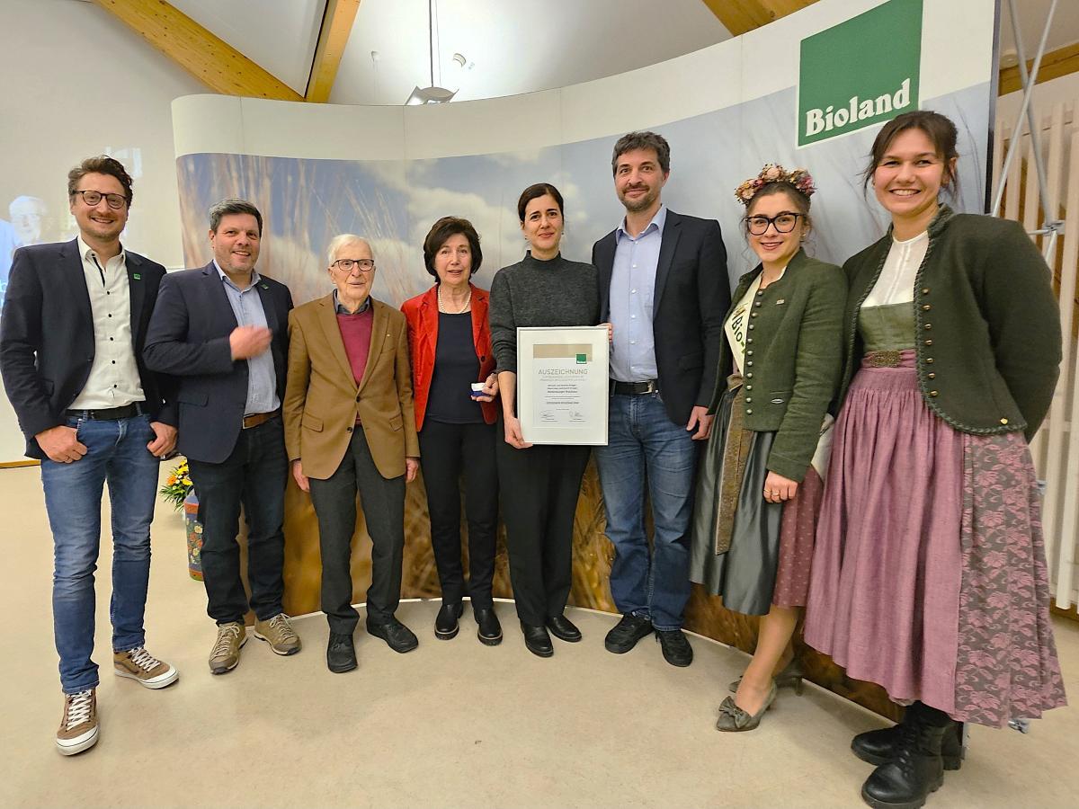 8 Personen, eine mit Urkunde, im Hintergrund Biolandbanner