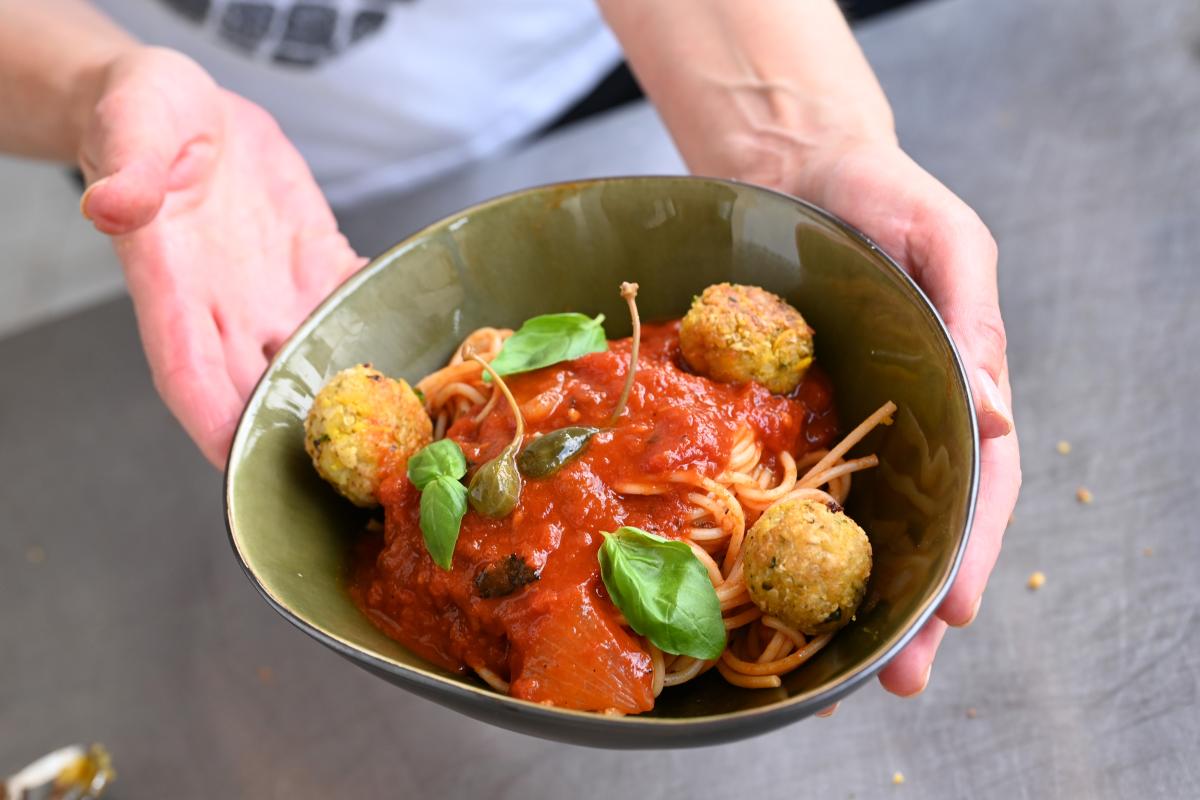 Schale mit Falafel und Tomatensauce, die jemand in den Händen hält