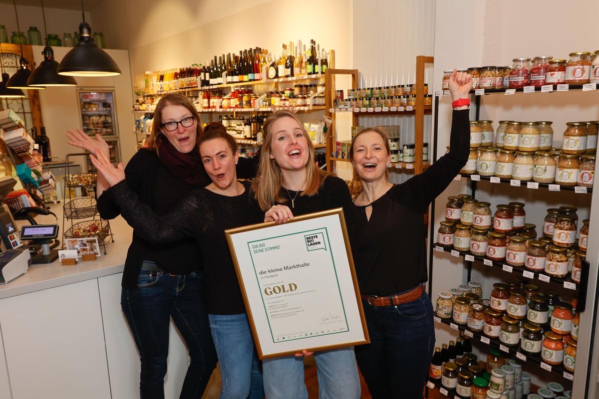 vier jubelnde Frauen in einem Laden mit einer GOLD Urkunde zum besten kleinen Bioladen