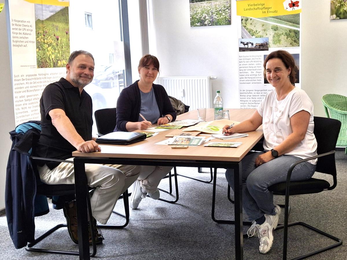 Drei Personen sitzen am Tisch