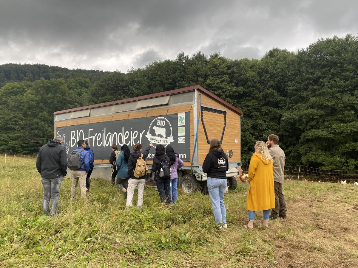 Gruppe steht vor einem mobilen Hühnerstall