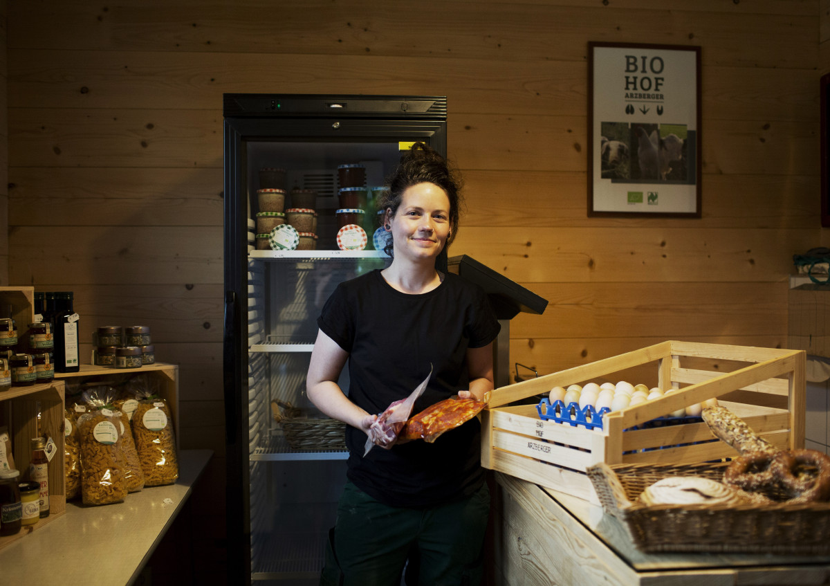 Julia Arzberger steht im Hofladen und hat ihre eigenen Produkte in der Hand