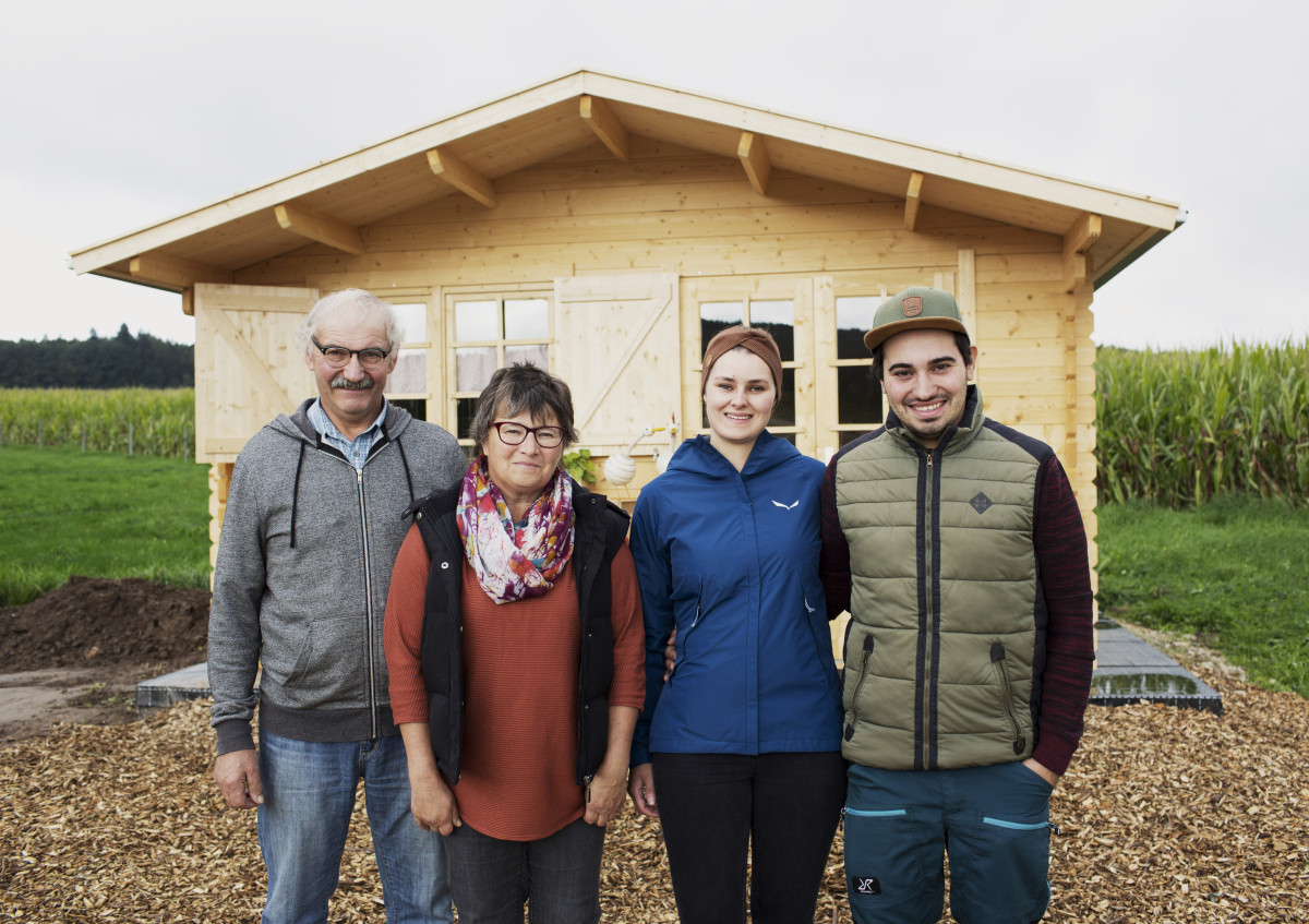 Mehrere Personen stehen vor einem Verkaufshäuschen aus Holz.