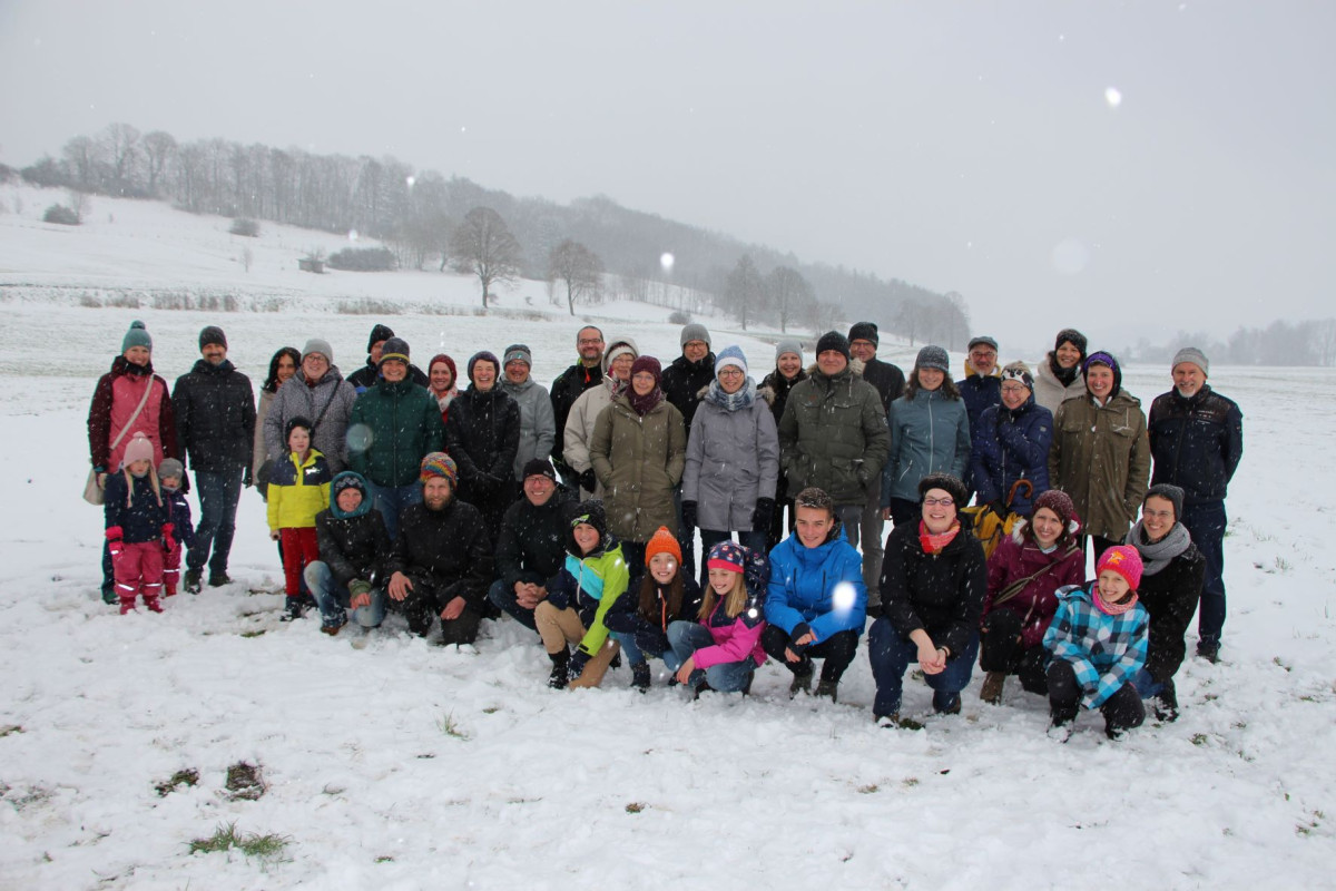 auf dem Bild sieht man viele Menschen mit warmer Kleidung , im Hindergrund sieht man schneebedeckte Felder