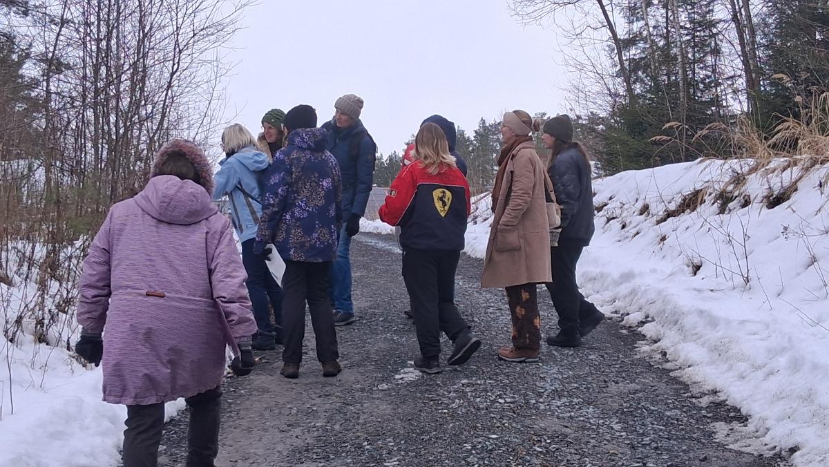 ein paar Menschen stehen gemeinsam zusammen und hören einer Rednerin zu