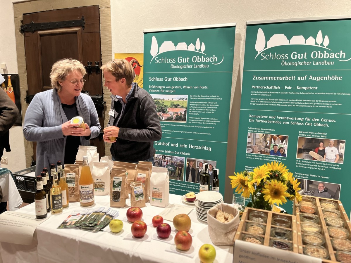 Zwei Frauen hinter einem Marktstand mit landwirtschaftlichen Erzeugnissen