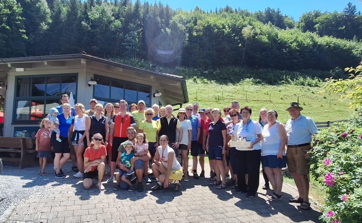 Gruppe an Menschen vor Pavillon und grüner Wiese