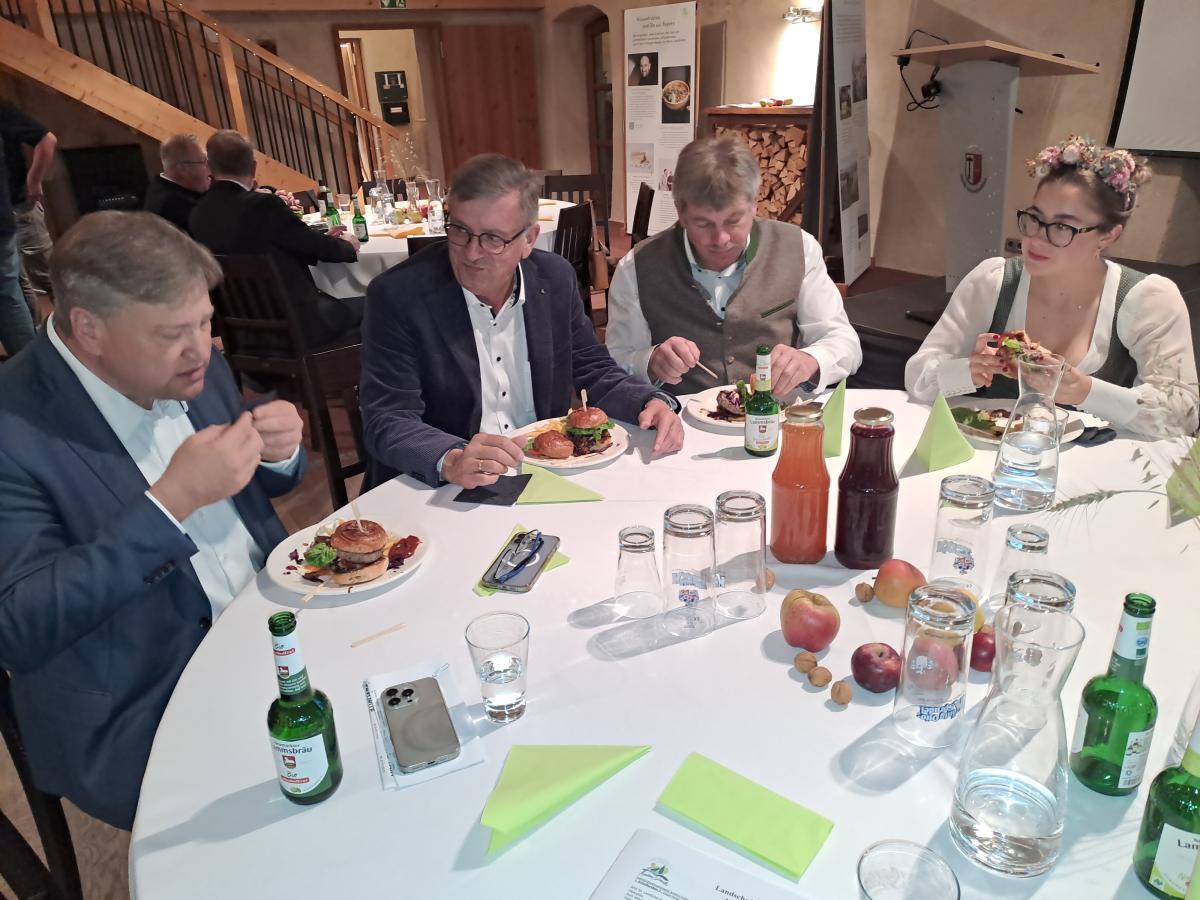 Mehrere Personen sitzen an einem Tisch und essen Burger.