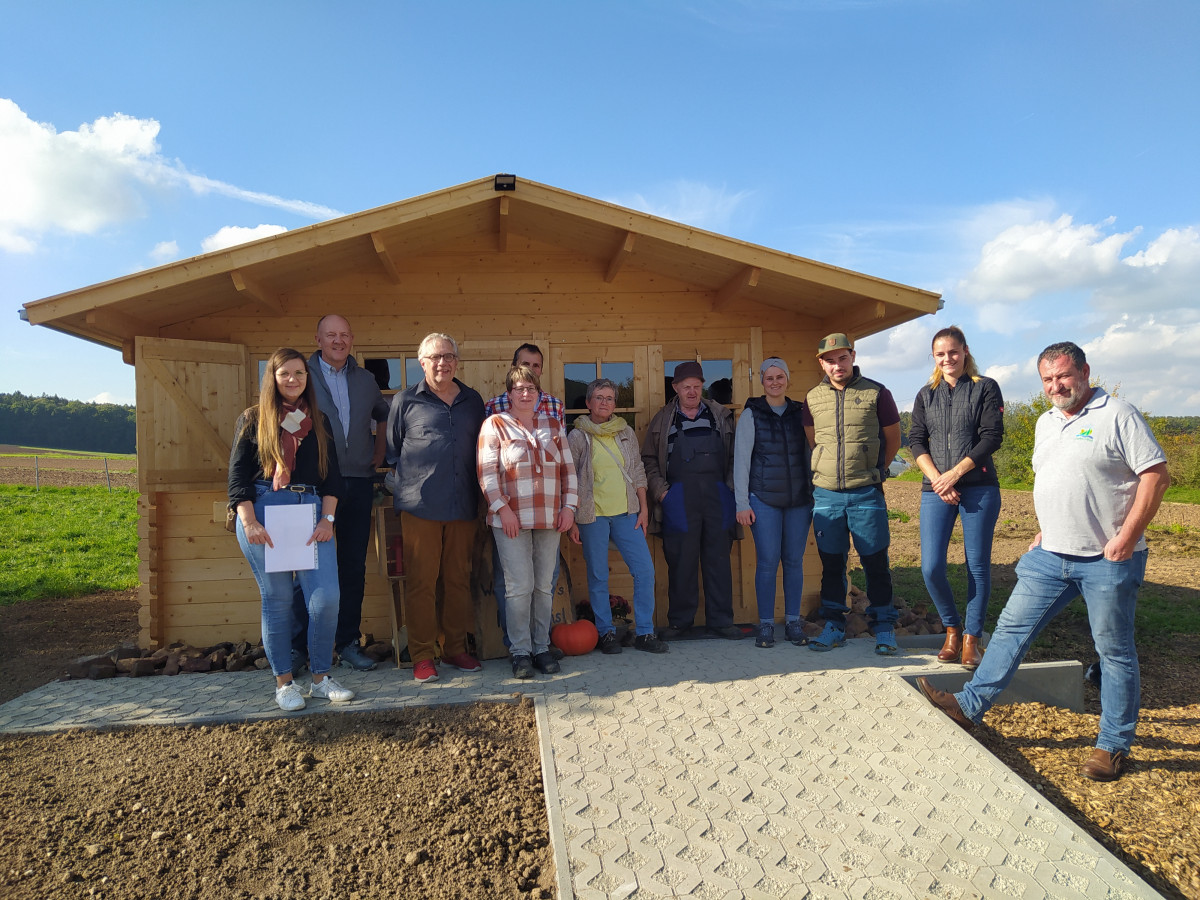 Eine Gruppe von Leuten steht vor einem Verkaufshäuschen aus Holz.