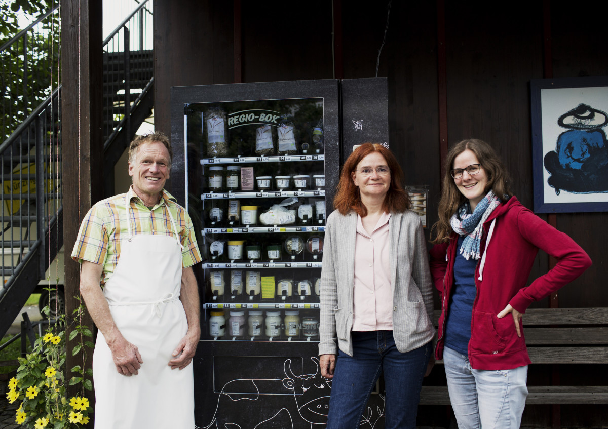 drei Personen vor einem Selbstbedienwarenautomat