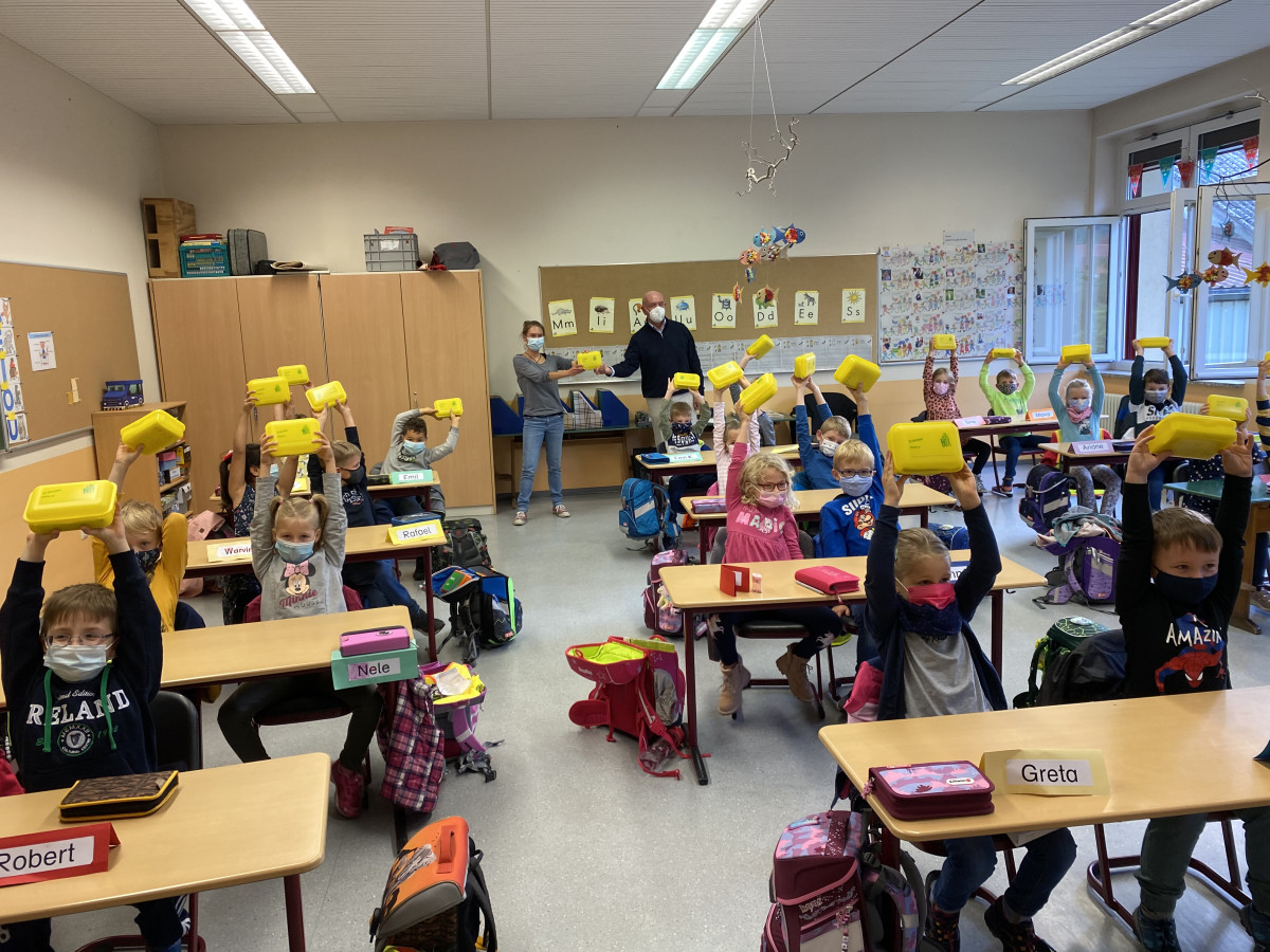 Schulklasse und Landrat Habermann und Maike Hamacher mit den gelben Brotboxen