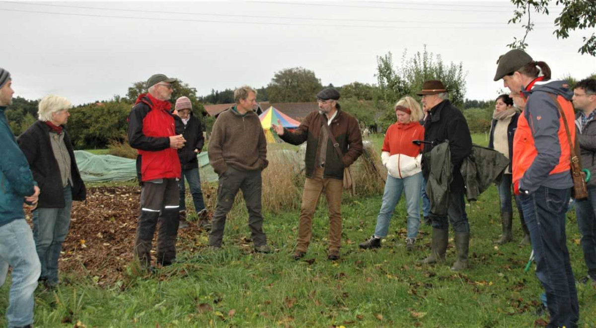 Betrachtung von Agroforstwirtschaft auf dem Feld des Blümlhofs - die teilnehmer stehen in Outdoor-Kleidung auf einem Acker