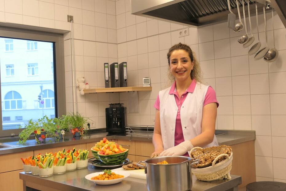Das Foto zeigt eine Frau in einer Küche mit vorbereiteten Speisen.