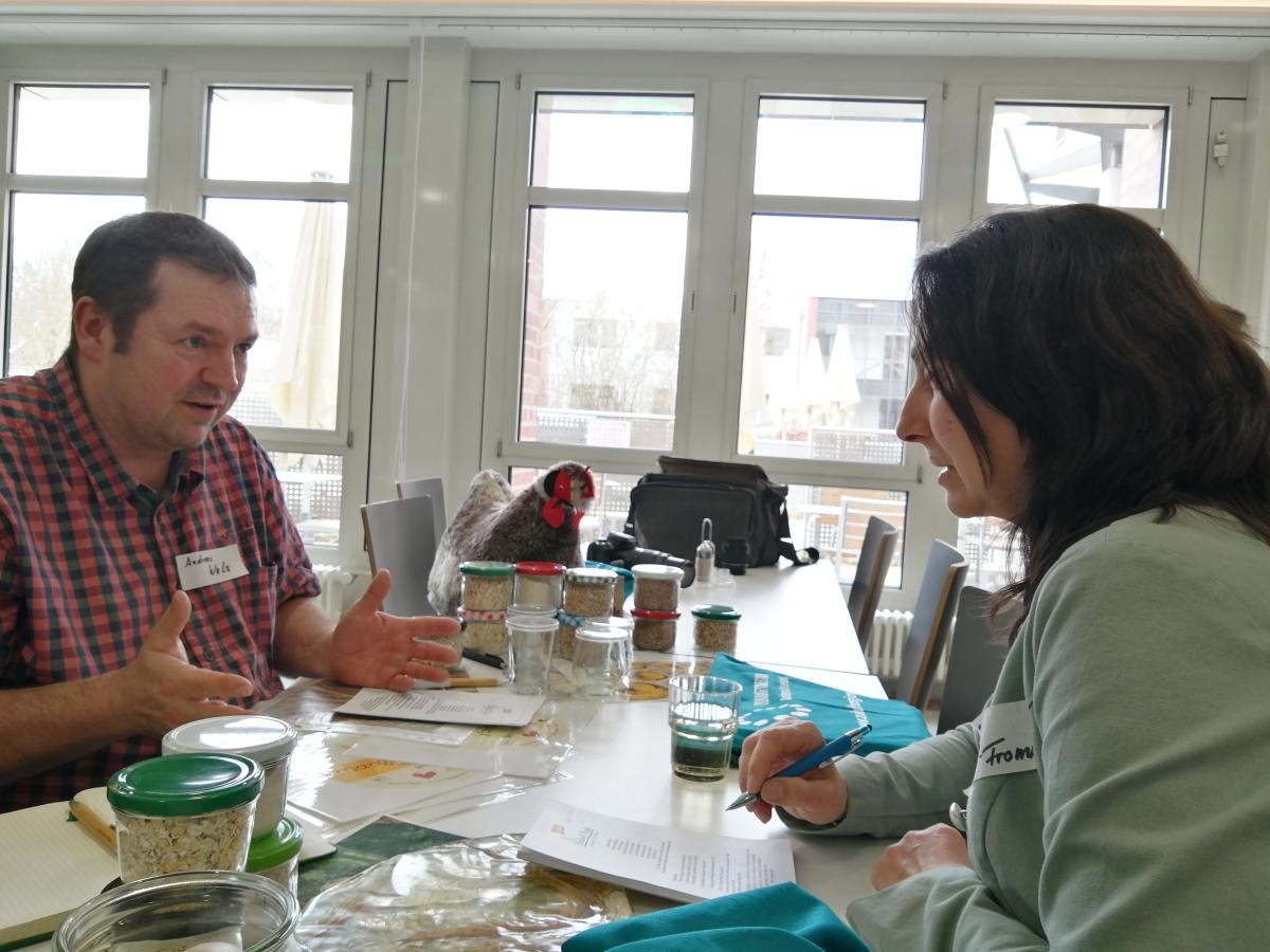 Ein Mann und eine Frau sitzen sich an einem Tisch gegenüber und reden miteinander.