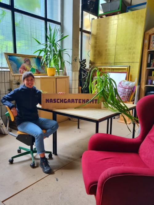 Eine Person am Schreibtisch mit Infoschild