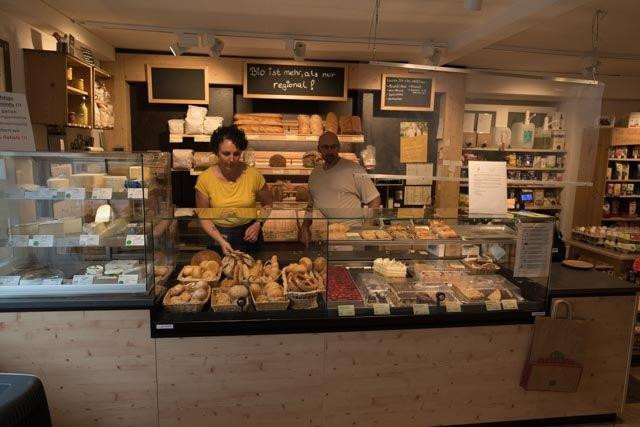 Barbara und Michael Wahlich hinter ihrer Ladentheke voller Käse-, Semmel-, Kuchenprodukte
