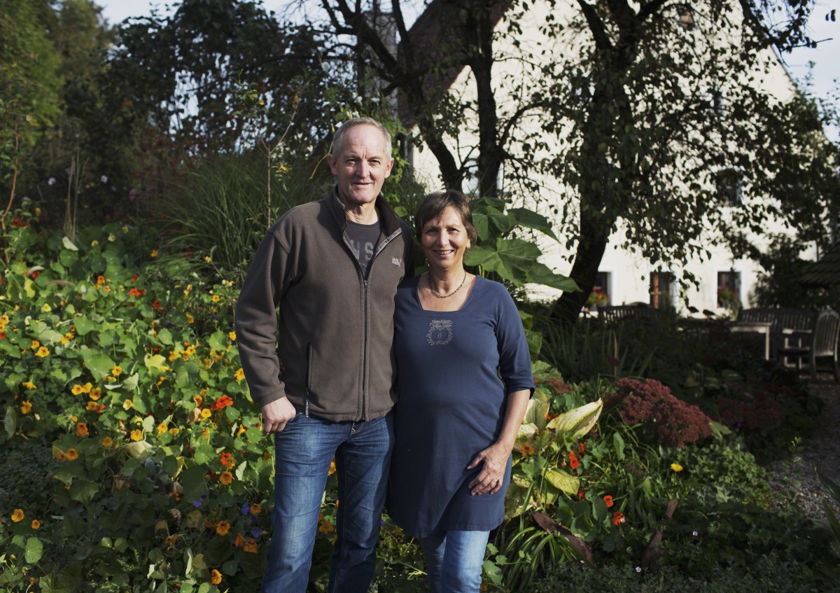 Ein Mann und eine Frau stehen Arm-in-Arm vor einem Baum