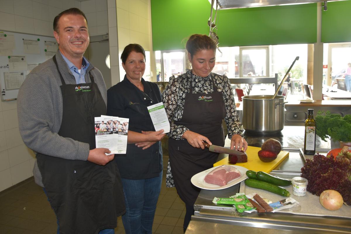 Drei Menschen in der Küche mit Flyern und beim Kochen