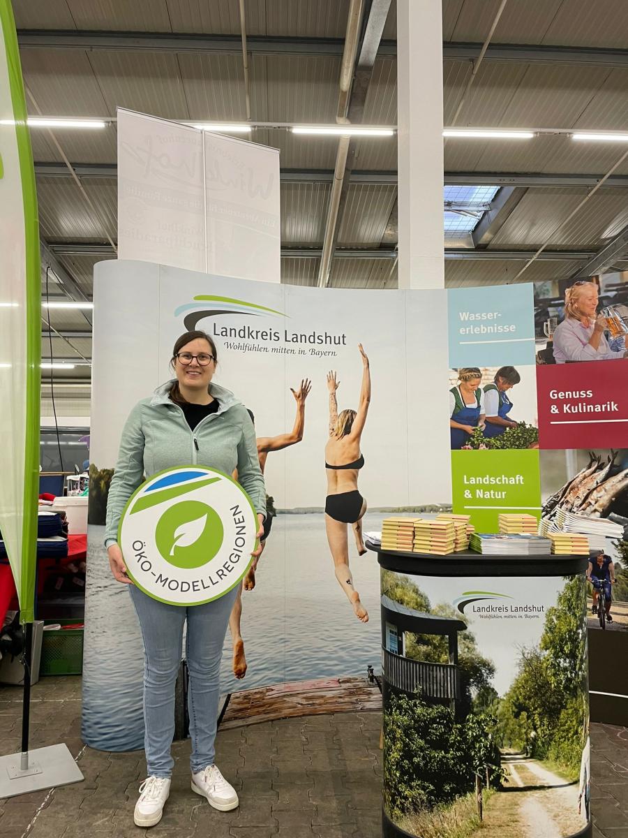 Veronika Stanglmayr mit Schild vor dem Stand vom Landkreis Landshut