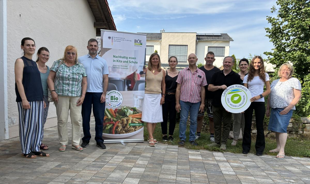 Gruppenfoto von Personen mit Bioland Aufsteller und Öko-Modellregionsschild