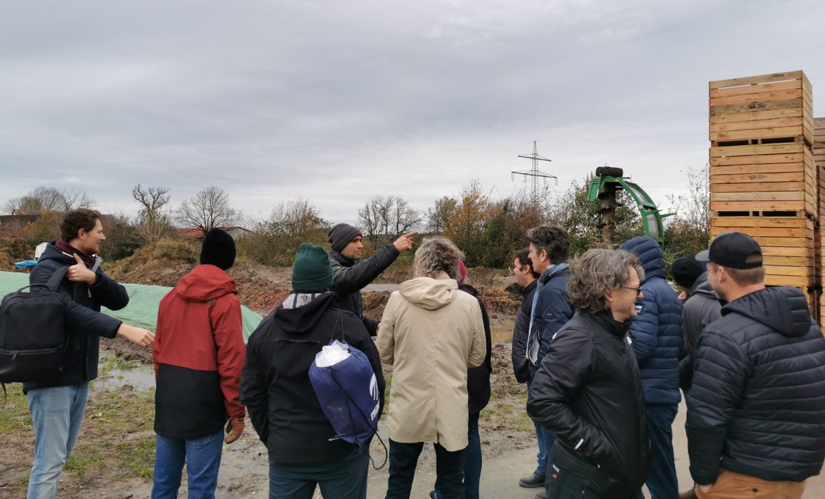 Das Foto zeigt einen Mann, der im Freien einer Gruppe etwas erklärt.