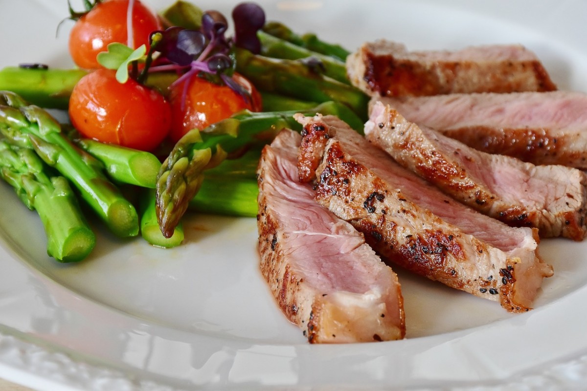 schön angerichtetes Menü mit Spargel, Tomaten und Fleisch