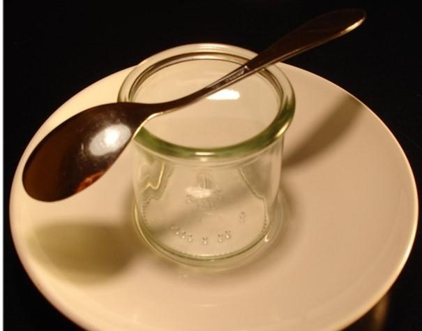 Löffel liegt auf einem Glas, das auf einem weißen Teller steht