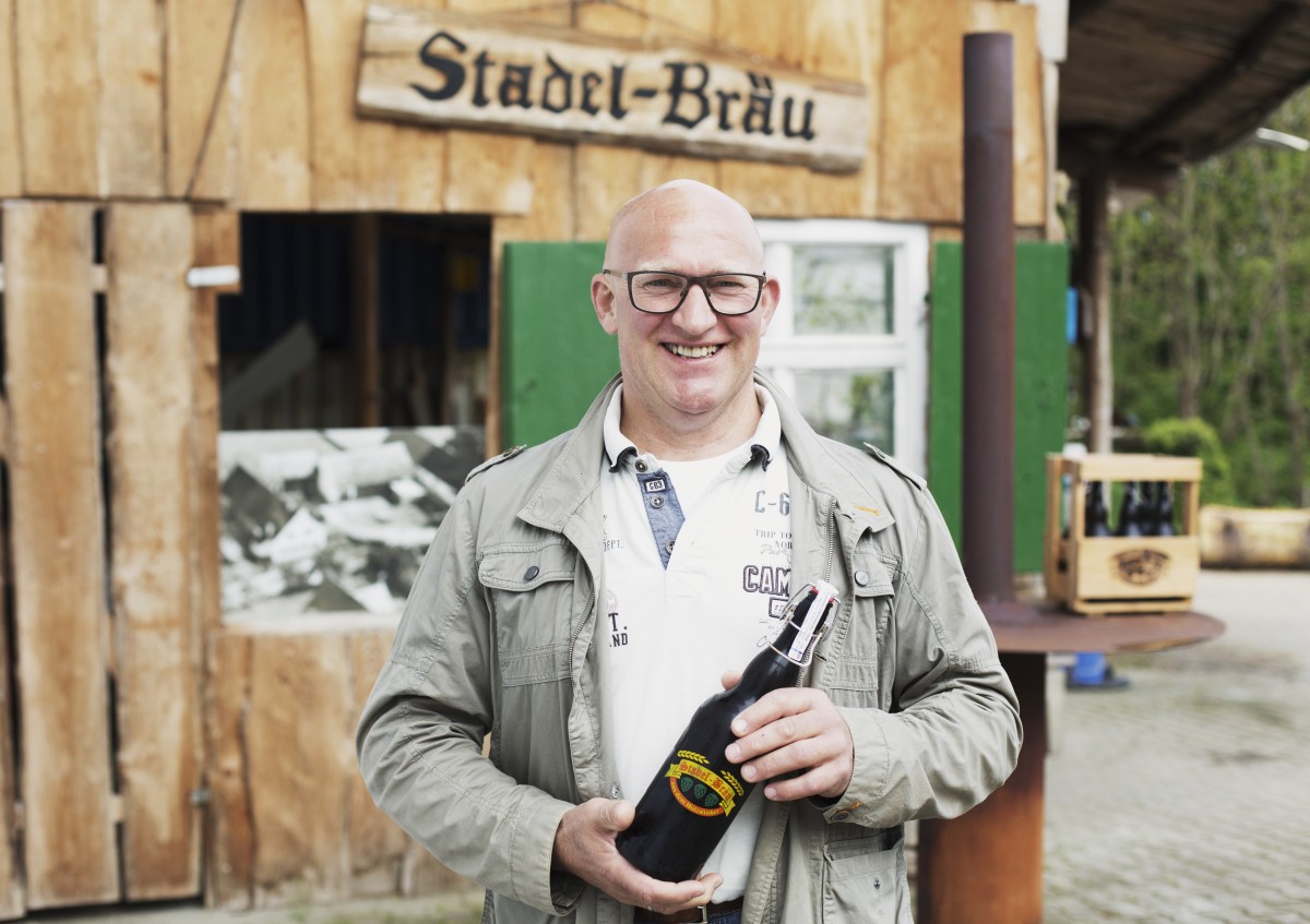 Das Foto zeigt einen Mann, der eine große Flasche Bier in der Hand hält.