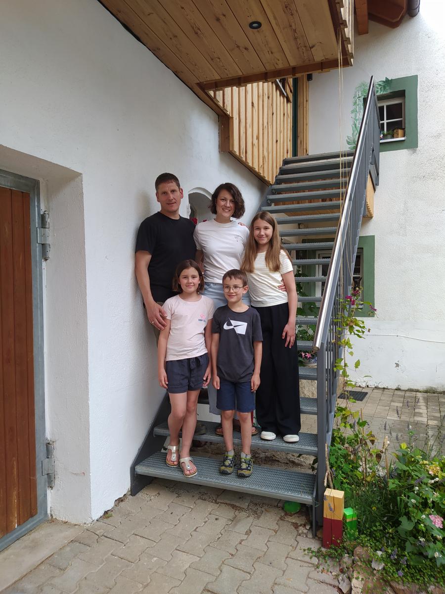 Eine Familie aus fünf Personen steht auf einer Treppe.
