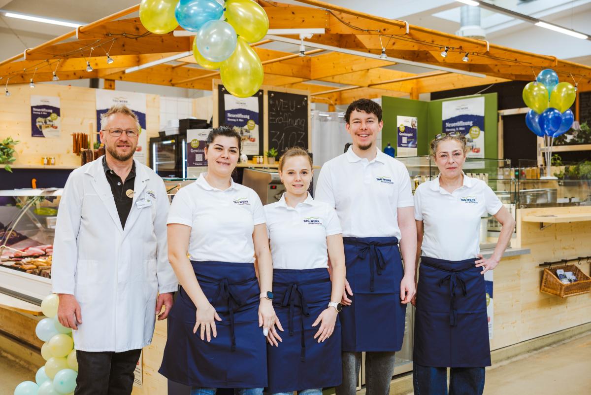 Das Foto zeigt mehrere Personen in einheitlicher Kleidung vor einem Verkaufsstand