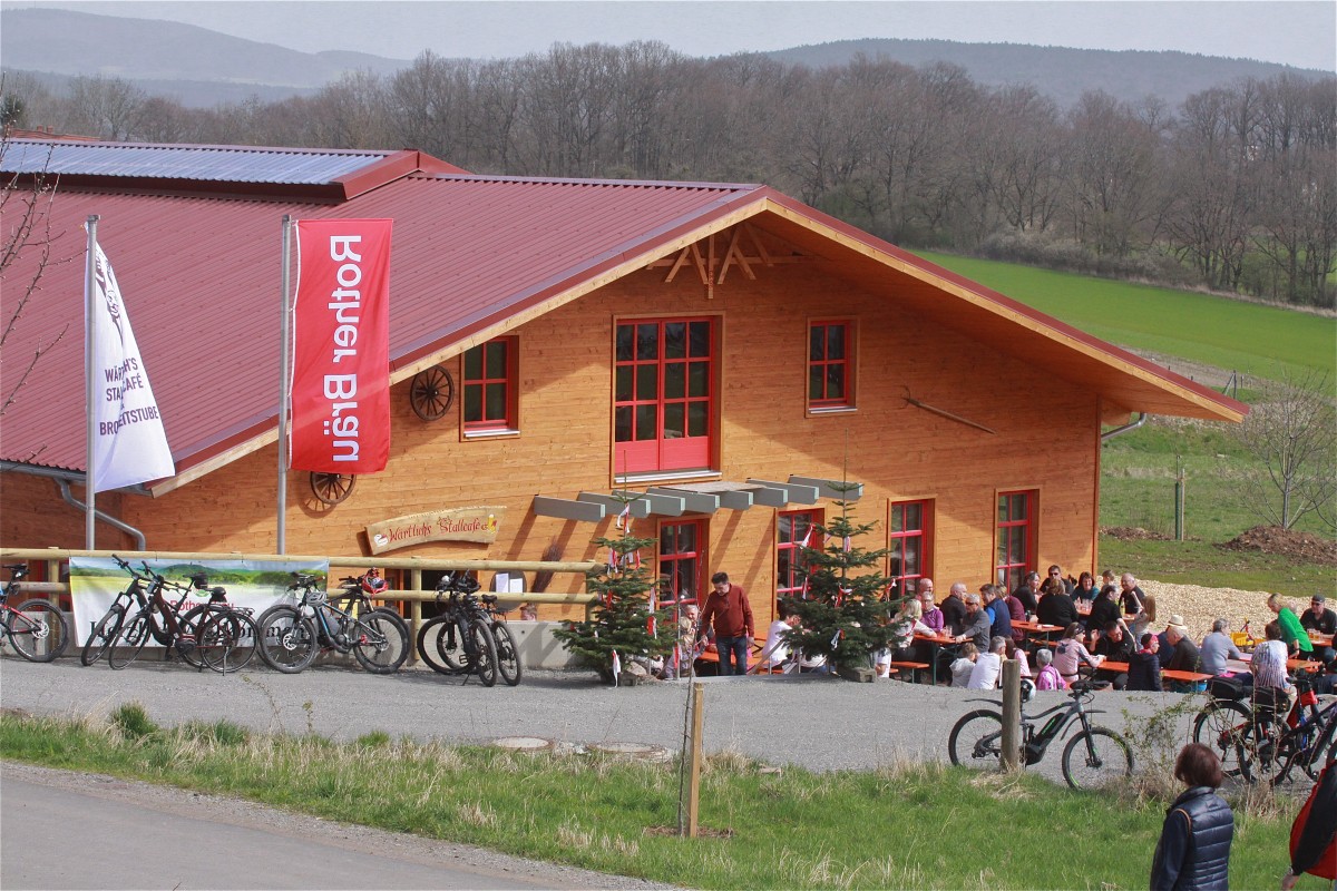 Blick auf Holzhaus mit Beuschern im Außenbereich