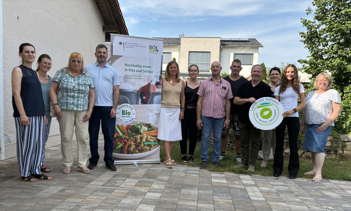 Gruppenfoto von Personen mit Bioland Aufsteller und Öko-Modellregionsschild
