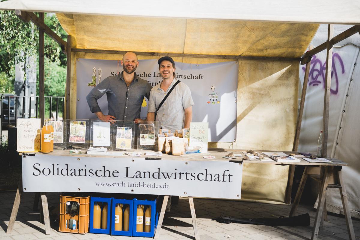 Ein Marktstand mit 2 Menschen und Infomaterialien