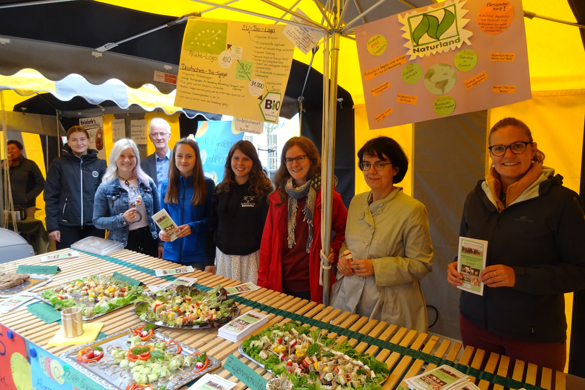 Infostand mit Häppchen, Plakate zu Bio-Betrieben und Personen