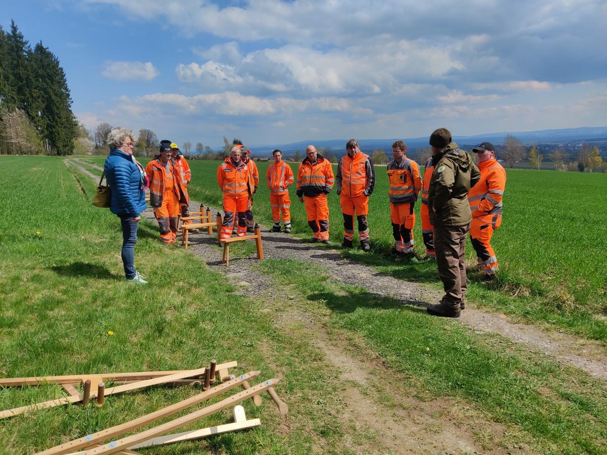 Mehrere Leute welche orange gekleidet sind stehen vor einem Ranger