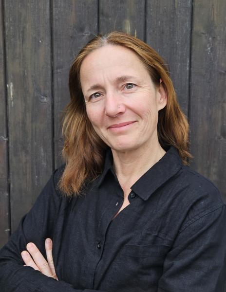 Person mit langen roten Haaren vor einer Holzwand