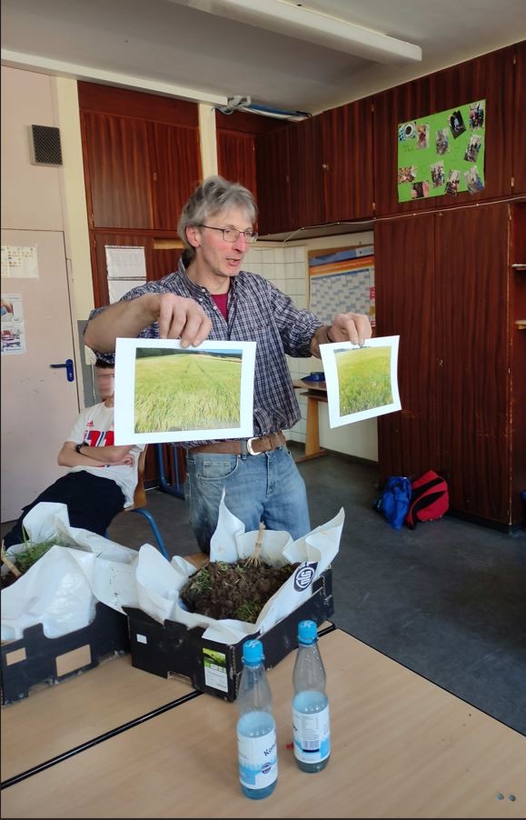 Andreas Kunz zu Besuch in der AG Öko der Mittelschule Tirschenreuth und er zeigt der Klasse 2 Bilder von Äckern