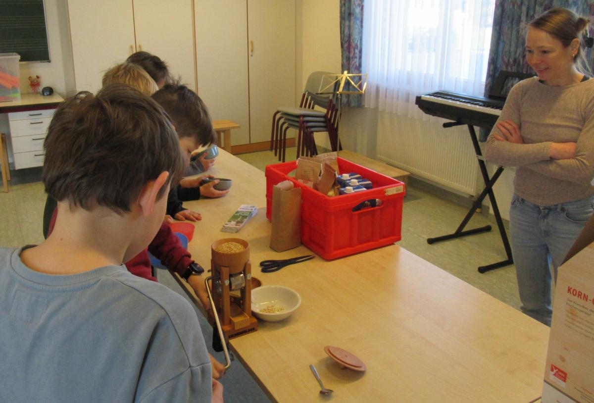 Mit Eifer quetschen Kinder mit Dr. Christina Lichtmannegger-Nowak von der Öko-Modellregion Waginger See-Rupertiwinkel Nackthaferkörner zu Haferflocken.