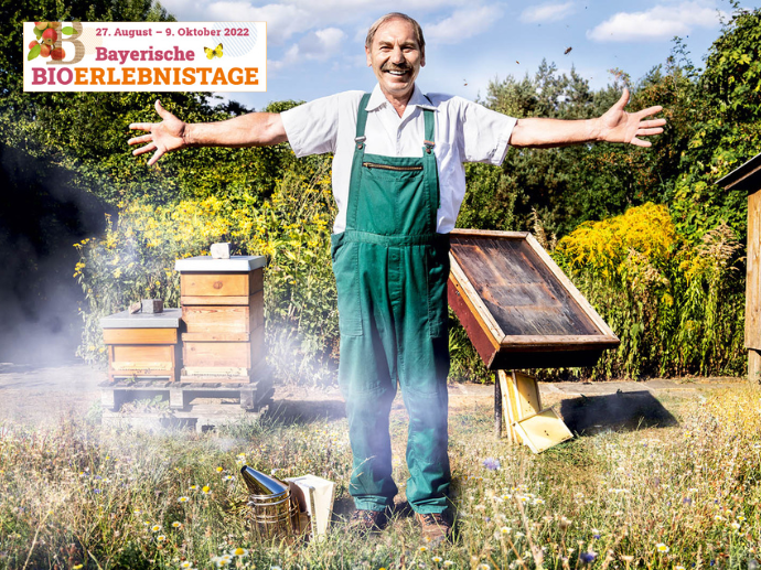 Toni Herzing mit ausgebreiteten Armen vor Bienenstock