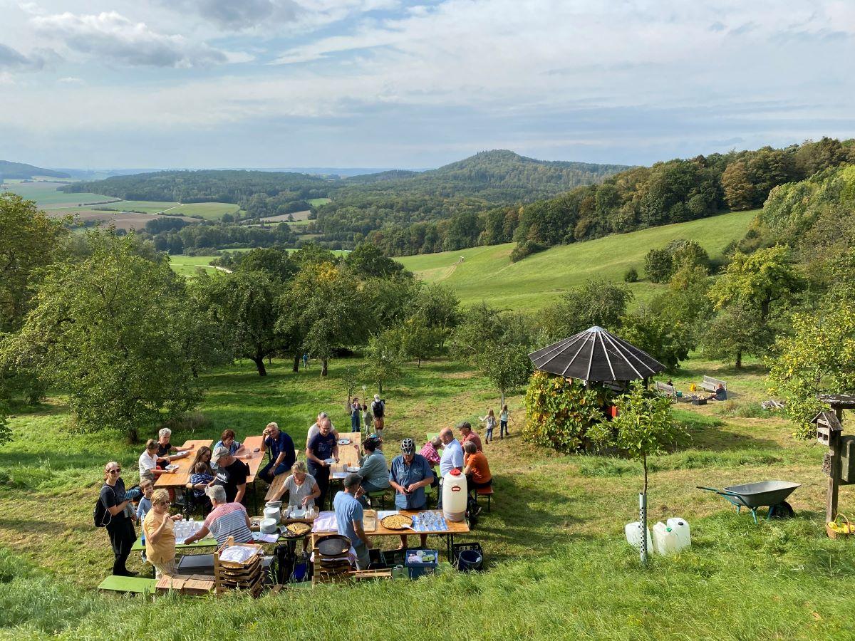 Festgäste genießen an Biertischen Apfelstrudel in der Streuobstwiese