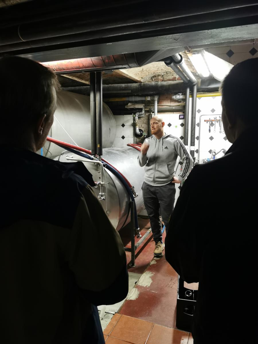 Das Foto zeigt einen Mann, der vor Lagertanks steht und etwas erklärt.