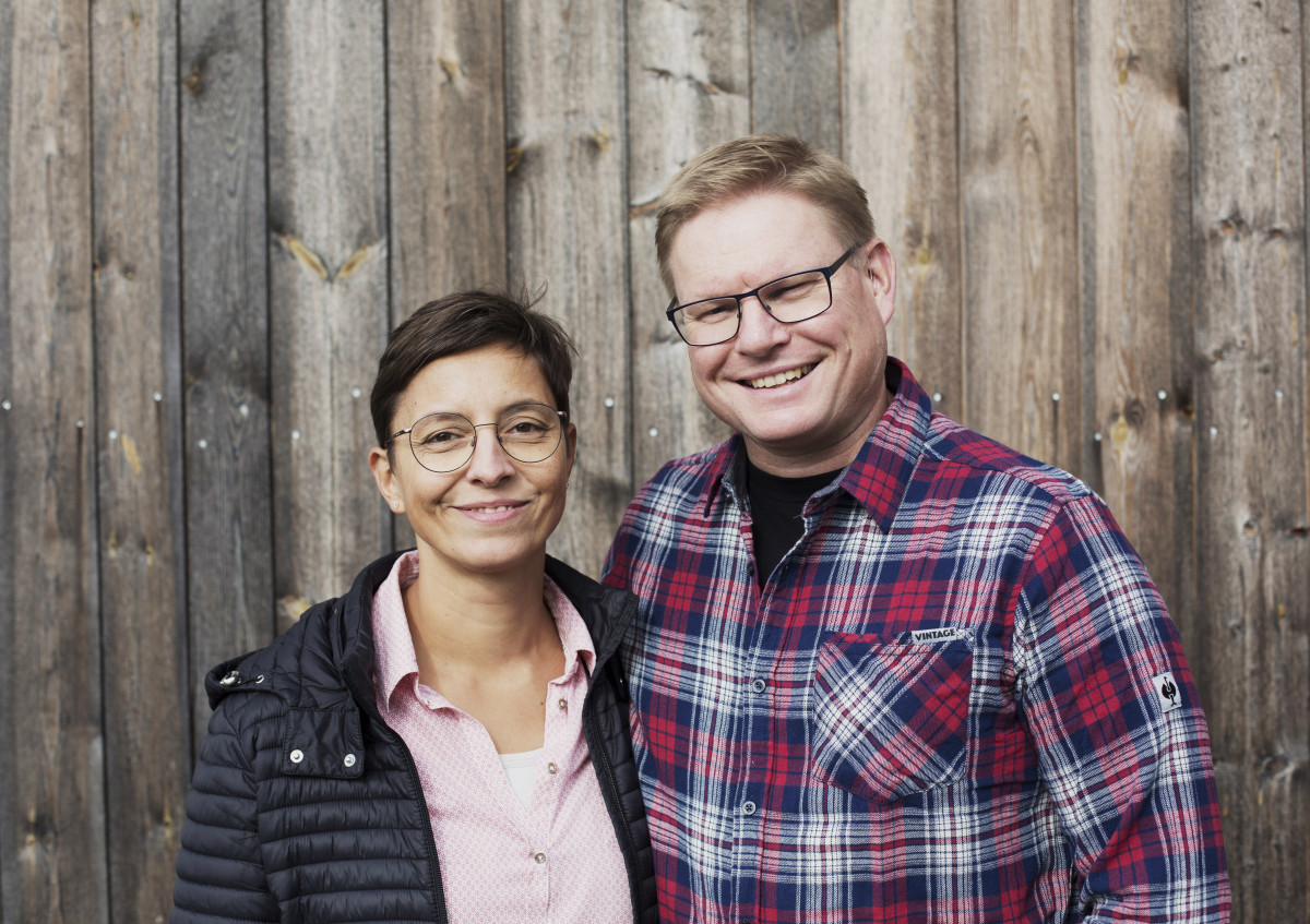 Martina und Peter Fuhrmann stehen vor einer holzverkleideten Außenwand