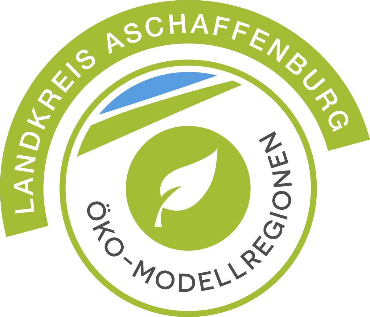Logo der Öko-Modellregion. Ein Blatt in der Mitte umgeben von einem Kreis mit dem Schriftzug Öko-Modellregion. Über dem Kreis steht in einem grünen gebogenen Kasten Landkreis Aschaffenburg.