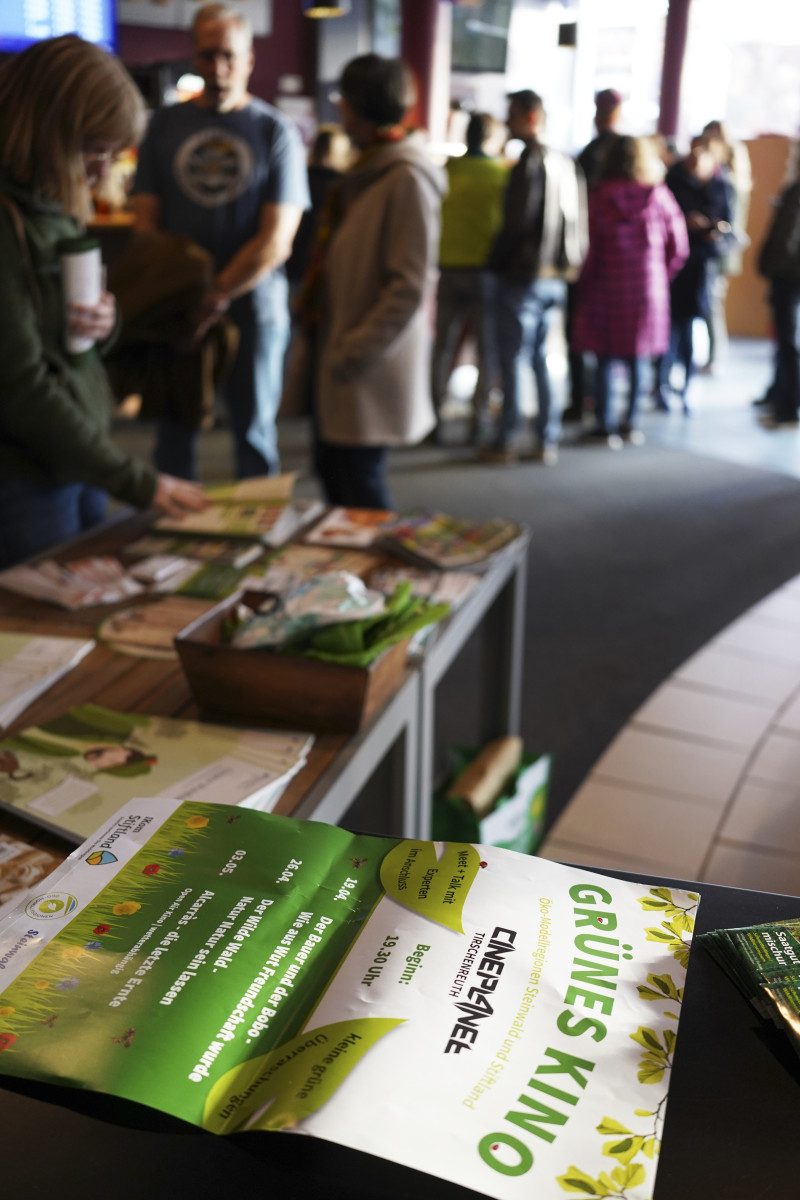 Besucher kommen ins Kino und bestaunen die Buchausstellung des Bücherhauses Rhode