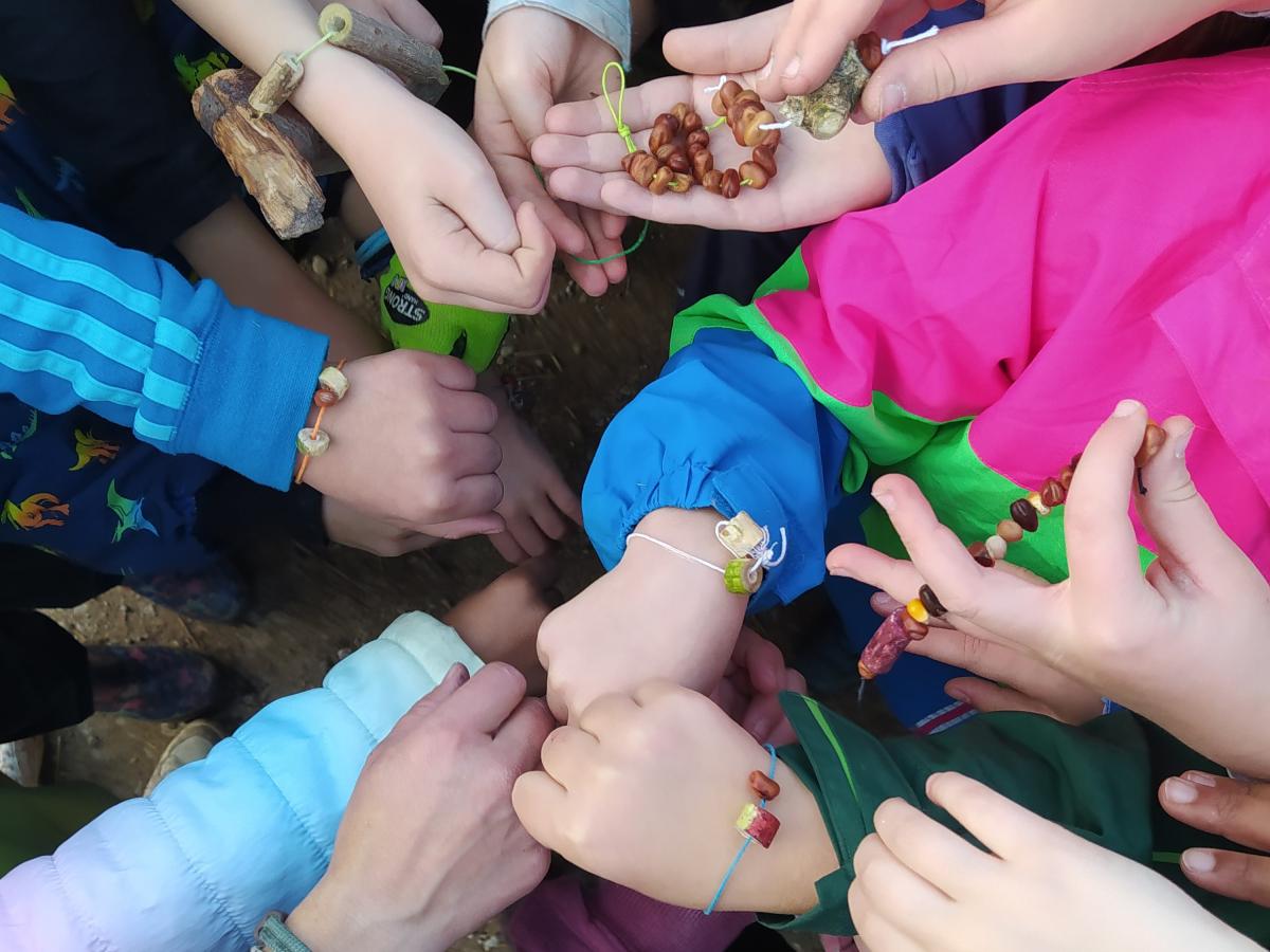 Kinder zeigen ihre Handgelenke mit selbstgemachten bunten Armbändern.