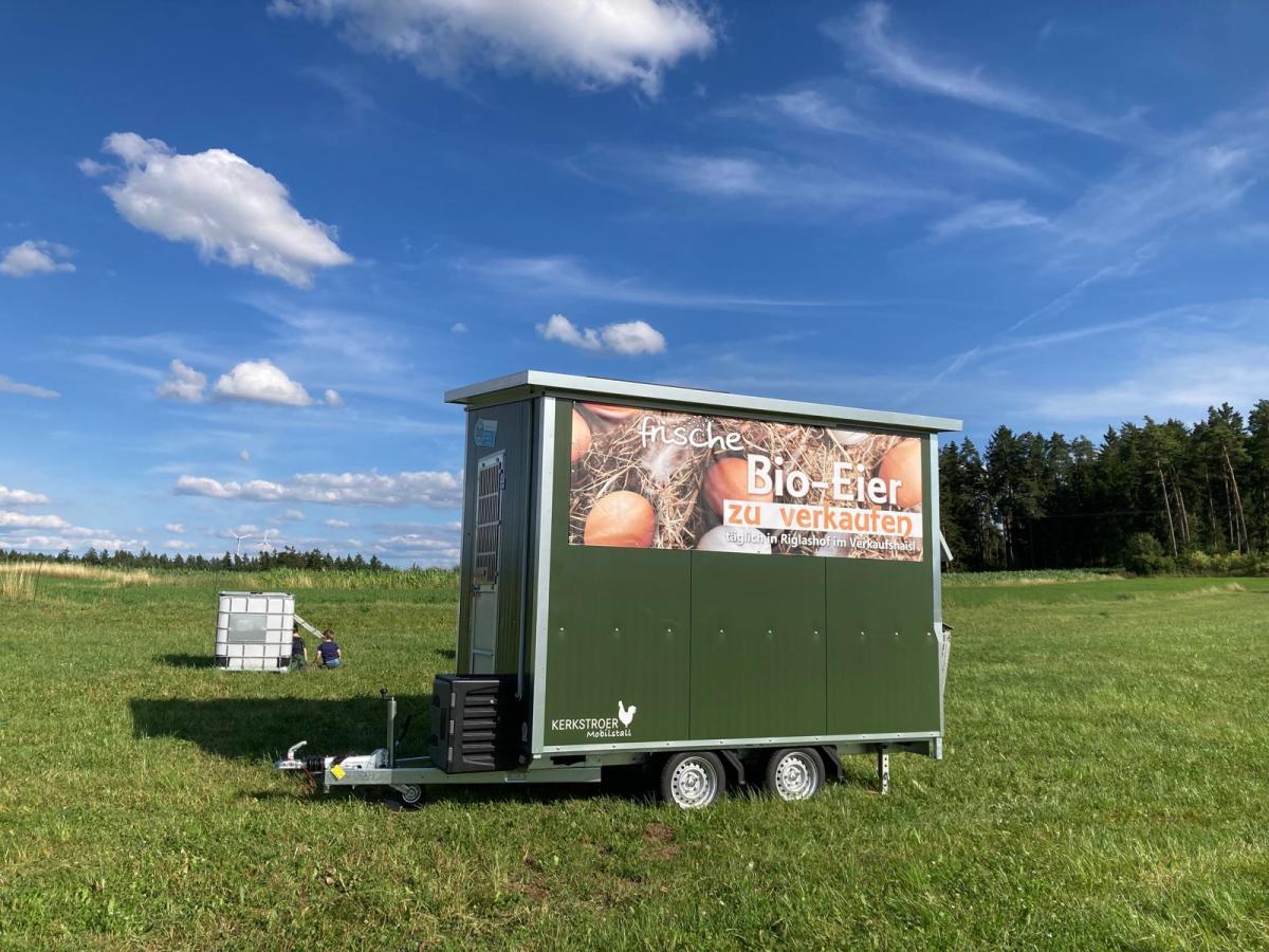 Ein Hühnermobil steht auf einer Weidefläche.